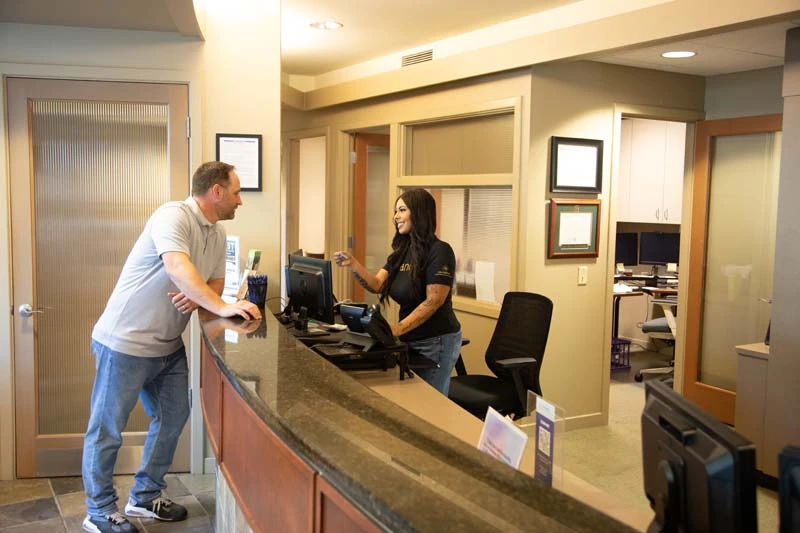 The skilled supportave team at Olympia Advanced Dentistry in Olympia, WA speaking with a male patient. 