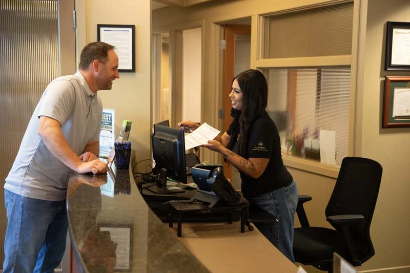Middle ages patient checking in at the front desk to discuss dental implant options at